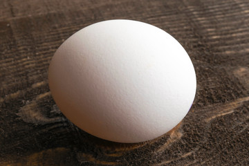 white chicken egg lay on brown wooden table