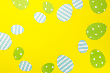 Green and blue paper Easter eggs on a yellow background. Easter background and holiday card.