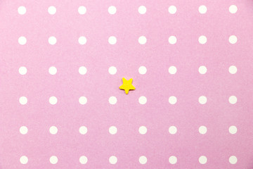 Small yellow star on a pink background with white small circles. Empty background. Postcard.
