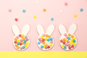 Three paper Easter bunny with candies on a pink background.. Easter background and greeting card. 