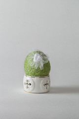 Oeuf décoré d'une ficelle verte dans son coquetier en porcelaine
