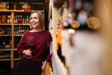 Image of woman with wine glass in store on background of shelves