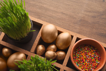 Easter composition with golden eggs, sprinkles and green grass