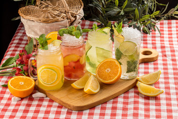 Fototapeta premium Set cold lemonade with lemon, orange and peach on wooden board on textile napkin