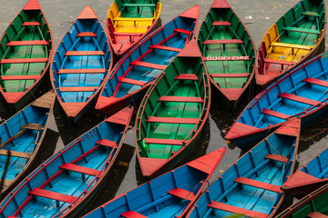 Traditional colored wooden rowing boats in Pokhara, Nepal an early morning before they go out onto...