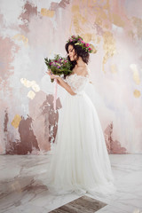 Elegant brunette girl bride with flowers. Beautiful young bride in a lush wedding wreath of fresh flowers