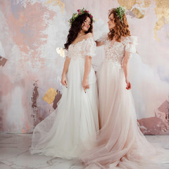 Two charming brides in beautiful spring wreaths on their heads. Beautiful young women in wedding dresses