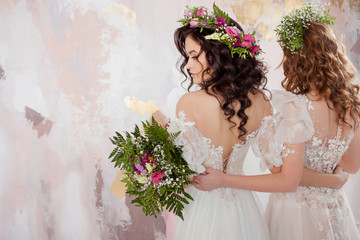 Two charming brides in beautiful spring wreaths on their heads. Beautiful young women in wedding dresses
