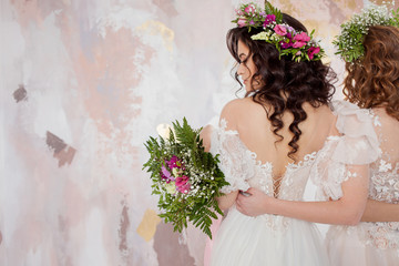 Two charming brides in beautiful spring wreaths on their heads. Beautiful young women in wedding dresses