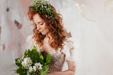 Portrait of a young beautiful woman in wedding dress with wreath and bouquet of fresh flowers.