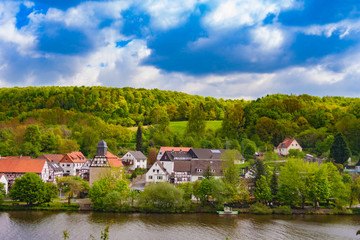 Fototapeta na wymiar Beautiful landscape scenery of the small village Staufenberg in Lower Saxony, Germany at the river Fulda on a nice sunny day and behind lies the large and densely wooded Münden Nature Park.