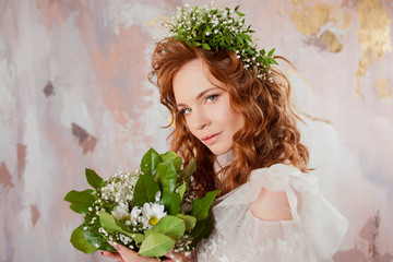 Portrait of a young beautiful woman in wedding dress with wreath and bouquet of fresh flowers.