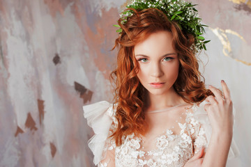 Portrait of a young beautiful woman in wedding dress with wreath of fresh flowers.