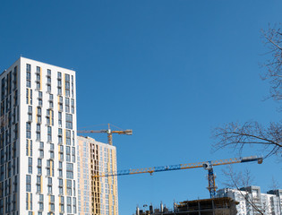 Fototapeta premium few modern freshly build residential buildings and crane at construction site. clear blue sky on background