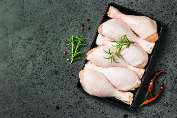Raw chicken legs, spicy marinated drumsticks in cast iron sheet pan on dark background. Top view, space for text.