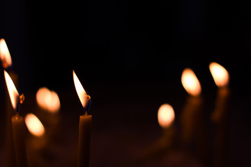 candle silent interior object in dark black environment and unfocused yellow fires bokeh simple...