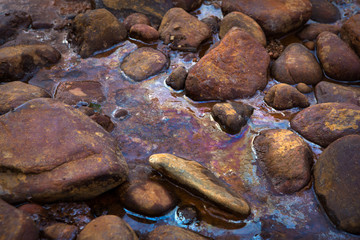 Oil spill. Water and stones in oil.