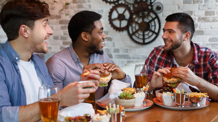 Friends enjoying burgers and beer in bar