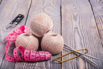 Balls of yarn, knitting needles and measuring tape on a wooden background.