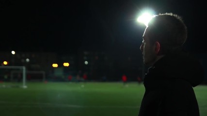 The guy is watching football training at the evening stadium - Powered by Adobe