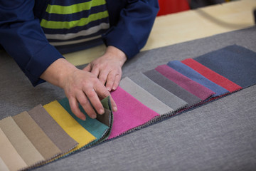 Closeup of an older woman in a furniture factory who is picking the material for the sofa