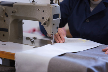 Closeup of an older woman in a furniture factory who is sewing the material for the sofa