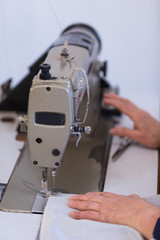 Closeup of an older woman in a furniture factory who is sewing the material for the sofa