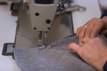 Closeup of an older woman in a furniture factory who is sewing the material for the sofa