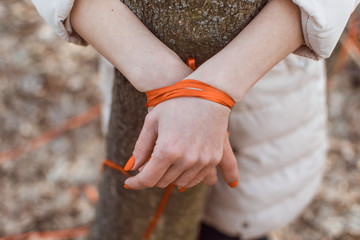 Restraint of women concept. A woman with her hands tied to a tree.