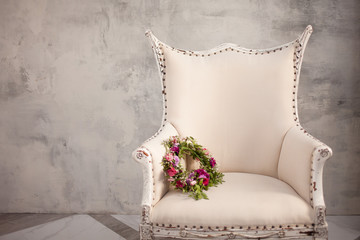 Wedding wreath of fresh red flowers, lying on an elegant cream chair