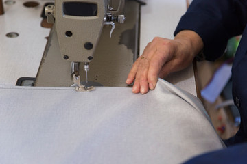 Closeup of an older woman in a furniture factory who is sewing the material for the sofa