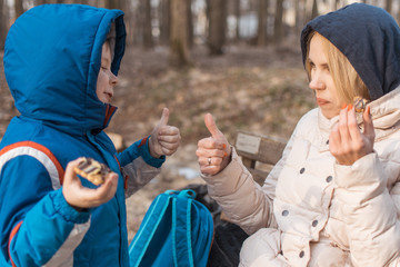 A little boy with his mother eat in the forest. The interaction of mother and child.
