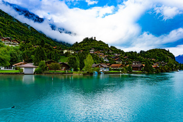 Fototapeta na wymiar Natural landscape of clear blue lake with mountains and villages in cloudy day