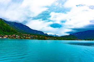 Natural landscape of clear blue lake with mountains and villages in cloudy day