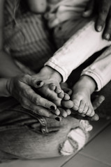 mom and dad hold their baby's bare feet in their hands black and white photography