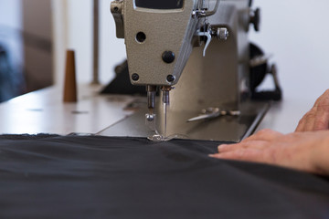 Closeup of an older woman in a furniture factory who is sewing the material for the sofa