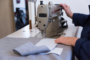 Closeup of an older woman in a furniture factory who is sewing the material for the sofa