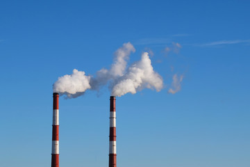 Pipes in the city with smoke, against a blue sky background. Environmental problem of environmental...