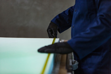 Young man in a furniture factory is measuring the foam for the sofa.