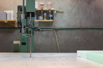 Portrait of a young man in a furniture factory cutting the foam for the sofa