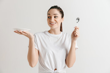 Young fun crazy brunette housewife with spoon isolated on white background. Housekeeper woman...