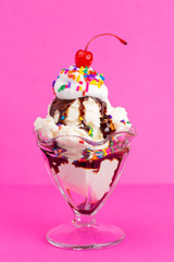 A Vanilla Sundae with Sprinkles and Chocolate Sauce on a Pink Background
