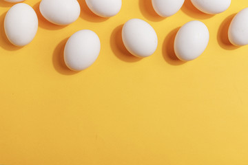 Set of white chicken eggs on a yellow background. Preparation for painting Easter eggs. Top view.