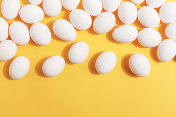 Set of white chicken eggs on a yellow background. Preparation for painting Easter eggs. Top view.