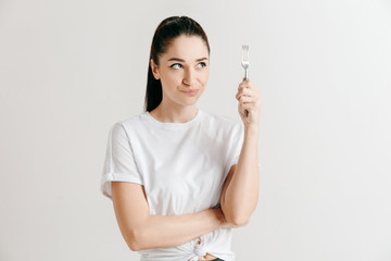 Young fun crazy brunette housewife with fork isolated on white background. Housekeeper woman...