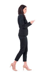Busy business woman multitasking walking and reading messages on mobile phone. Full body isolated on white background.