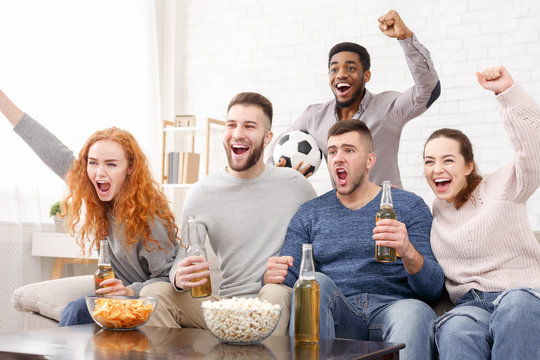 Group of friends watching football and celebrating victory
