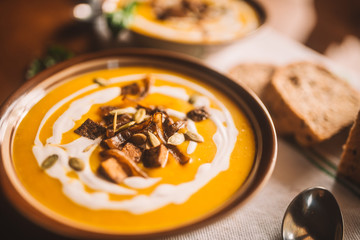  tasty autumn coconut pumpkin cream soup bowl with tofu, caramelized onion and seeds