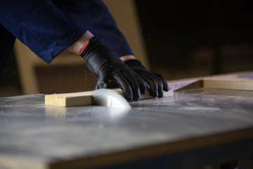 Close up of a young man in a furniture factory cutting the wooden pieces for the sofa