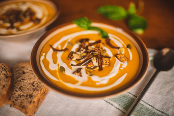  tasty autumn coconut pumpkin cream soup bowl with tofu, caramelized onion and seeds